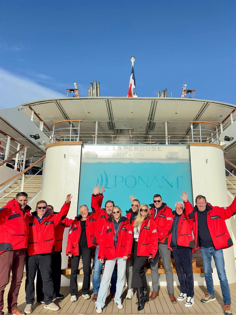 Reisgezelschap in rode expeditiejassen aan boord van een expeditieschip